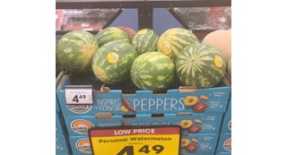 Watermelons placed on a stack of boxes labelled peppers